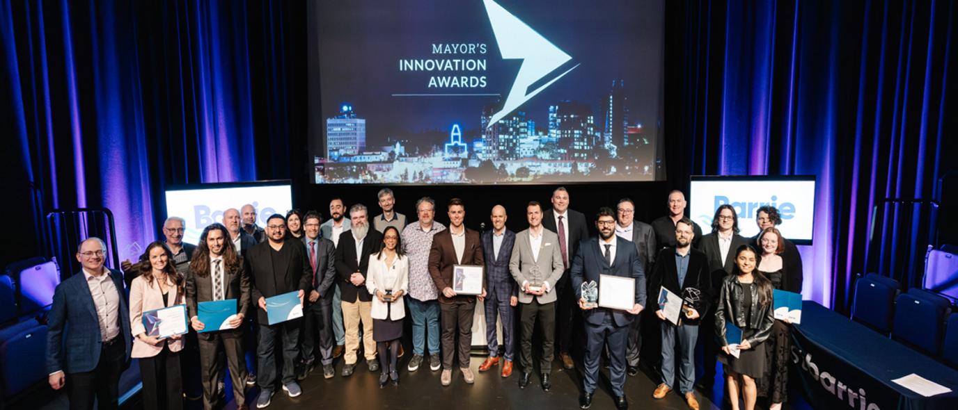 Awards ceremony group photo on stage with blue lighting.
