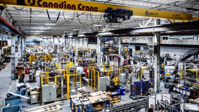 Interior of factory. There are people working along the manufacturing assembly line.