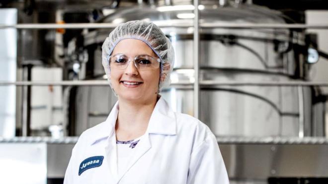 Technician dressed in ppe standing in front of industrial machinery.