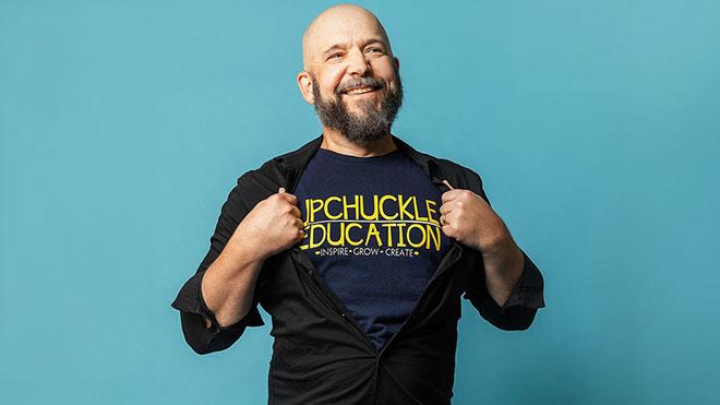 Brad standing and smiling at camera, showing shirt with UPCHUCKLE EDUCATION printed on it