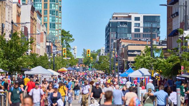 Businesses set up with event tents on Dunlop Street in downtown Barrie, with crowds of people exploring