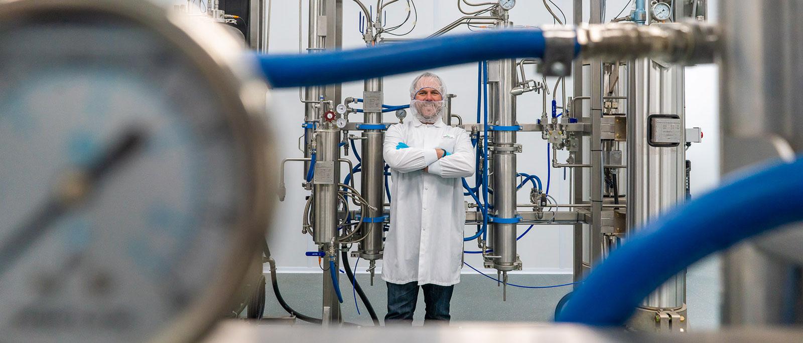 man in white lab coat standing with arms crossed