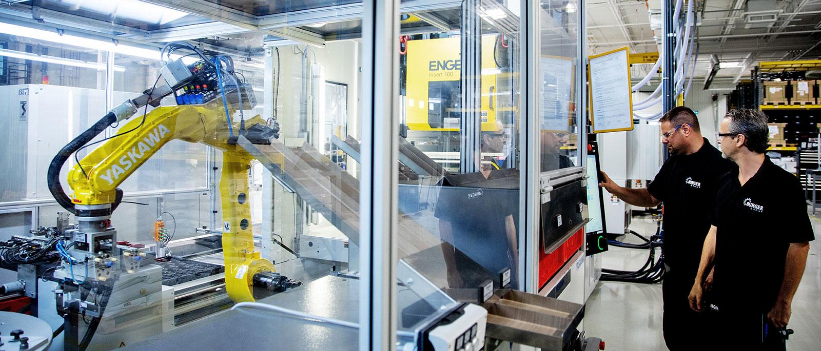 Factory workers operating robotic arm